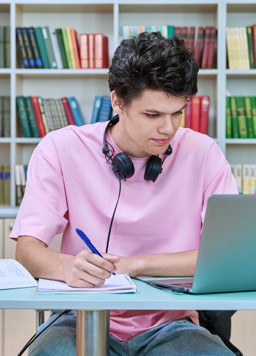 Student studying with laptop and notes.